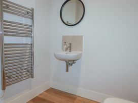 A bathroom with a sink, towel radiator, and mirror at Chi Gwynn in Crantock