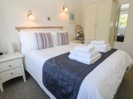 A bedroom with a bed, bedside table, towels, and wardrobe at Atlantic Waves in Carbis Bay