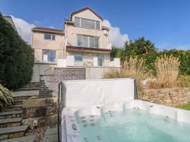 A hot tub in a garden with a house in the background at Bayside in Carbis Bay