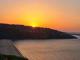 A sunset over water with hills and houses at Sea Mist in Carbis Bay