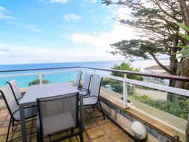 A balcony with a table and chairs overlooking the sea at Ocean Gem in Carbis Bay