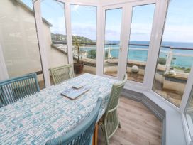 A conservatory with a table and chairs overlooking the sea at Ocean Gem in Carbis Bay