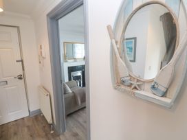 A hallway with a mirror and a view into a living room at Ocean Gem in Carbis Bay