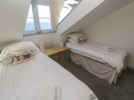 A bedroom with two beds and a window overlooking the sea at Ocean Gem in Carbis Bay