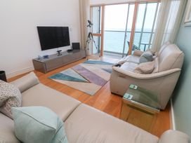 A living room with sofas a glass side table a wall mounted TV a patterned rug and a telescope facing the ocean at Elanora in Carbis Bay
