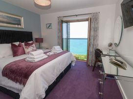 A bedroom with a bed topped with folded towels a glass desk and an open window with a sea view at Elanora in Carbis Bay