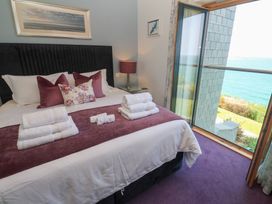 A bedroom with a bed with folded towels on it and a view of the sea through an open window at Elanora in Carbis Bay