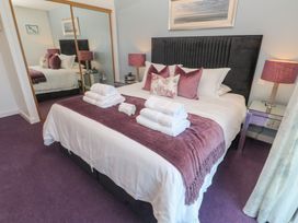 A bedroom with a bed with folded towels on a purple throw at Elanora in Carbis Bay