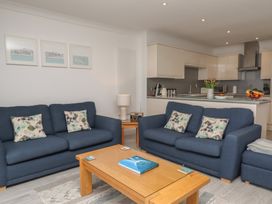 A living room with two blue sofas and a wooden coffee table in front of a kitchen at Harbour View in Carbis Bay