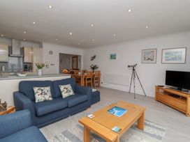 A living room with blue sofas a wooden coffee table a dining table and a television at Harbour View in Carbis Bay