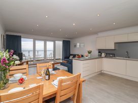 A kitchen and dining area with wooden table and chairs a sofa and glass doors leading to a balcony at Harbour View in Carbis Bay