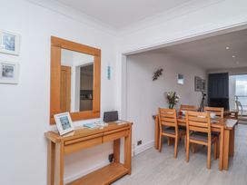 A dining area with a wooden table and four chairs next to a wooden console table with a large mirror on the wall at Harbour View in Carbis Bay