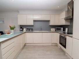 A kitchen with cream cabinets a stainless steel oven a microwave toaster kettle and flowers on the counter at Harbour View in Carbis Bay