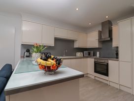 A kitchen with white cabinets and stainless steel appliances with a bowl of fruit on the counter at Harbour View in Carbis Bay