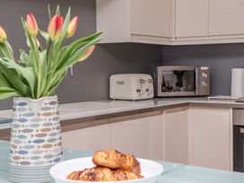 A kitchen corner with a toaster microwave and a vase of tulips at Harbour View in Carbis Bay
