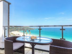 A balcony with a glass table and two chairs overlooking a beach and ocean at Harbour View in Carbis Bay