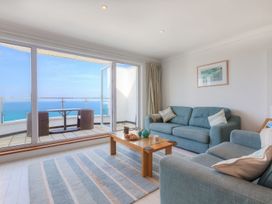 A living room with blue sofas coffee table and glass doors opening to balcony with sea view at Harbour View in Carbis Bay