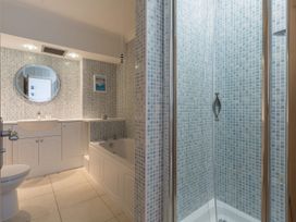 A bathroom with a bathtub a shower toilet and a sink with a mirror at Harbour View in Carbis Bay