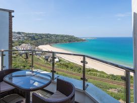 A balcony with glass railing overlooking a beach and blue sea at Harbour View in Carbis Bay