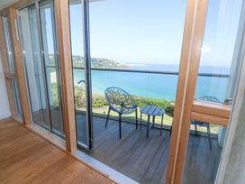 A balcony with two chairs and a small table overlooking the sea at Kittiwake in Carbis Bay