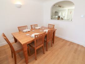 A dining room with a wooden table set for six next to a pass-through window to a kitchen at Sapphire in Carbis Bay