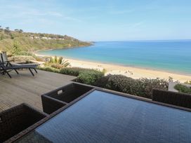 A deck with chairs and a table overlooking the beach at Sapphire in Carbis Bay