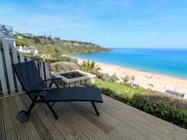 A deck with a chair overlooking the beach and ocean at Sapphire in Carbis Bay