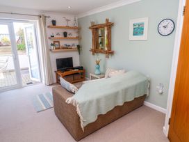 A living room with a sofa, tv, and shelving at Sea Breeze in Carbis Bay