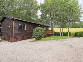 A cabin surrounded by trees and gravel area at Squirrels Leap Number 29, Burnside Park near Keswick