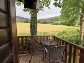 An outdoor seating area with a table and chairs overlooking a meadow at Squirrels Leap near Number 29, Burnside Park near Keswick
