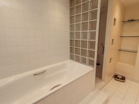 A bathroom with a bathtub and a glass block wall at ASTA COTTAGE in Cresswell