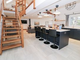 A kitchen with a staircase and bar stools at Merddwr in Cerrigydrudion