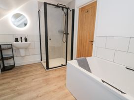 A bathroom with a shower, bathtub, sink, and towel at Merddwr in Cerrigydrudion
