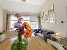 A living room with a dining table and flowers in a vase at Sea Pink Cottage in Langton Matravers