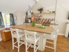 A kitchen with a table and bar stools at Sea Pink Cottage in Langton Matravers