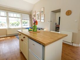 A kitchen with a wooden island and flowers in a vase at Sea Pink Cottage in Langton Matravers