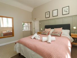 A bedroom with a bed, bedside tables, and a mirror at Sea Pink Cottage in Langton Matravers