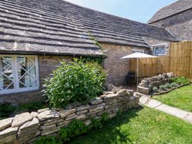 A garden with a stone wall and chairs at Sea Pink Cottage in Langton Matravers