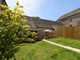 A garden with a stone building and a parasol at Sea Pink Cottage in Langton Matravers