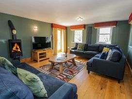 A living room with two blue sofas a wooden coffee table a television and a wood burning stove at Fron Goch Farm in Llanfair Talhaiarn