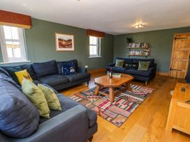A living room with two blue sofas a wooden coffee table and bookshelves at Fron Goch Farm Llanfair Talhaiarn