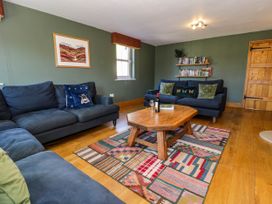 A living room with blue sofas a wooden coffee table and a patterned rug at Fron Goch Farm in Llanfair Talhaiarn