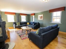 A living room with two dark sofas a wooden coffee table and a patterned rug at Fron Goch Farm in Llanfair Talhaiarn