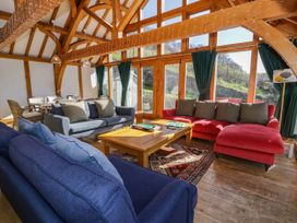 A living room with three sofas a wooden coffee table and large windows with green curtains at Fron Goch Farm in Llanfair Talhaiarn