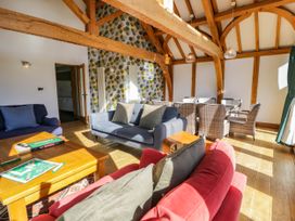 A living room with sofas a wooden coffee table and a dining table with wicker chairs at Fron Goch Farm in Llanfair Talhaiarn