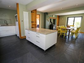 A kitchen and dining area with a central island and yellow chairs at Fron Goch Farm in Llanfair Talhaiarn