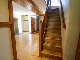 A wooden staircase and open wooden door in a hallway with wooden floors at Fron Goch Farm Llanfair Talhaiarn
