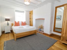 A bedroom with a wooden bed and orange pillows a white bedside table with a lamp a large mirror and a wooden wardrobe at Fron Goch Farm in Llanfair Talhaiarn