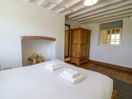A bedroom with a bed with white towels a wooden wardrobe a window and a wooden floor at Fron Goch Farm in Llanfair Talhaiarn