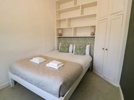 A bedroom with a bed with two green pillows two folded towels built in shelves and a white wardrobe at Fron Goch Farm in Llanfair Talhaiarn